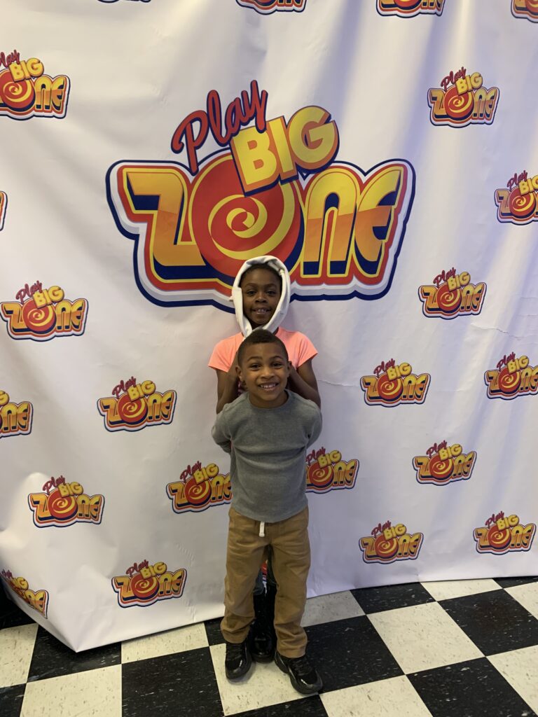Standing in front of the Play Big Zone banner